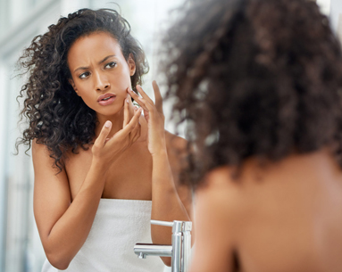Black female model in bathroom mirror checking her face
