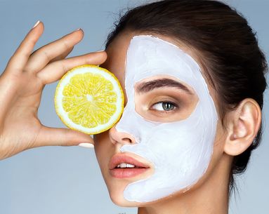 Woman with facial skin care mask and lemon covering one eye