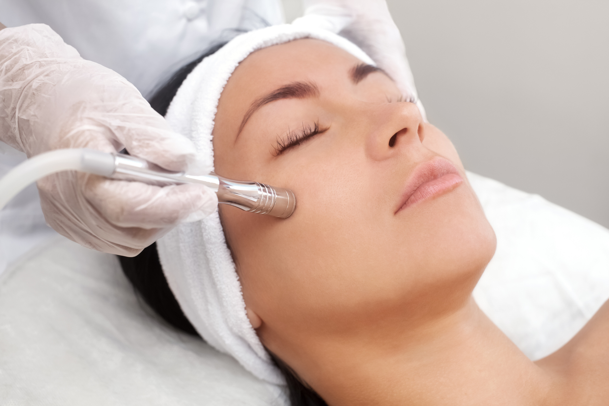 The cosmetologist makes the procedure Microdermabrasion of the facial skin of a beautiful, young woman in a beauty salon